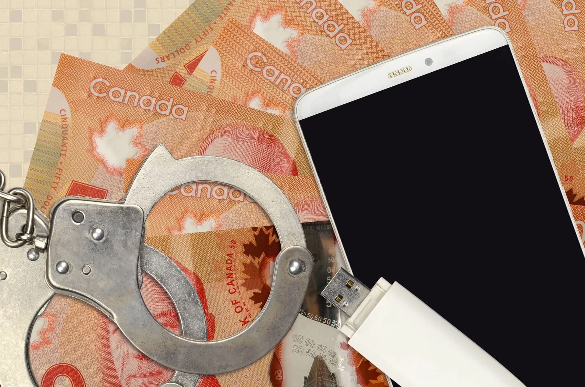 Handcuffs placed on Canadian dollar bills beside a smartphone and USB drive, symbolizing the intersection of financial crime, digital evidence, and criminal justice in Canada.