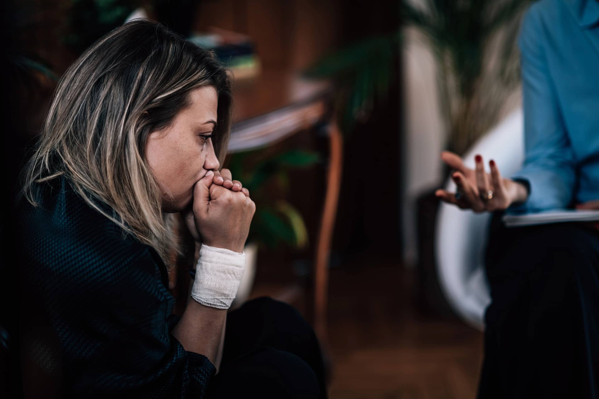 A woman on the floor, hand on her face, contemplating her options for finding a domestic violence lawyer in Toronto.